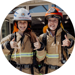 Photograph of school students Grace and Sophie dressed in firefighters uniforms in Hokitika at a job expo in Hokitika 