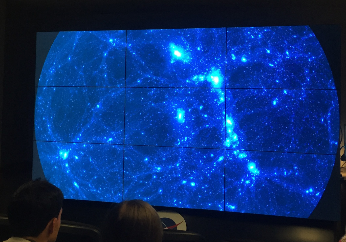People looking at a screen with the universe on it.