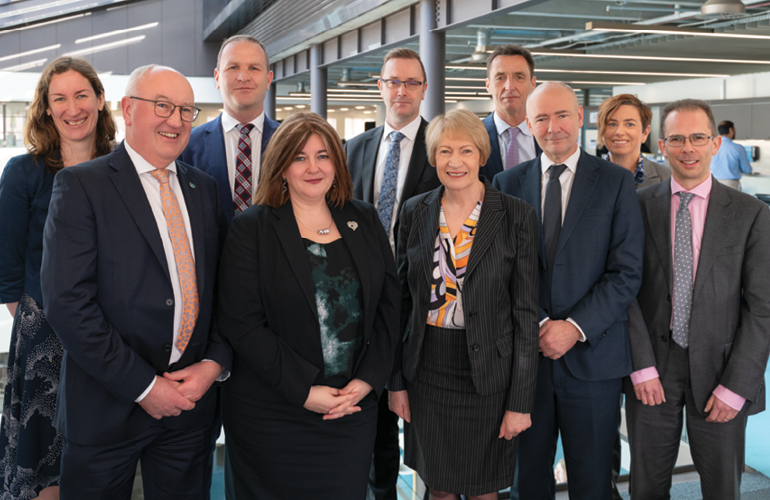 Portrait of the 10 people in MBIE's Senior Leadership Team, gathered inside with roof rathers behind them.