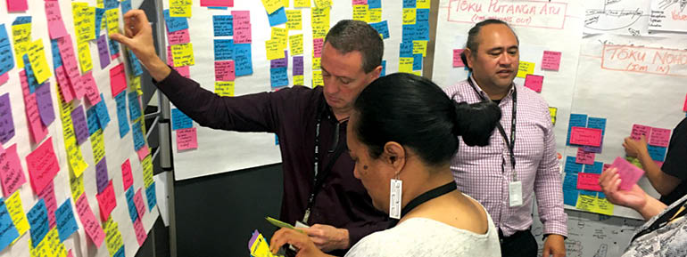 Decorative image: staff putting brightly-coloured sticky notes on boards.