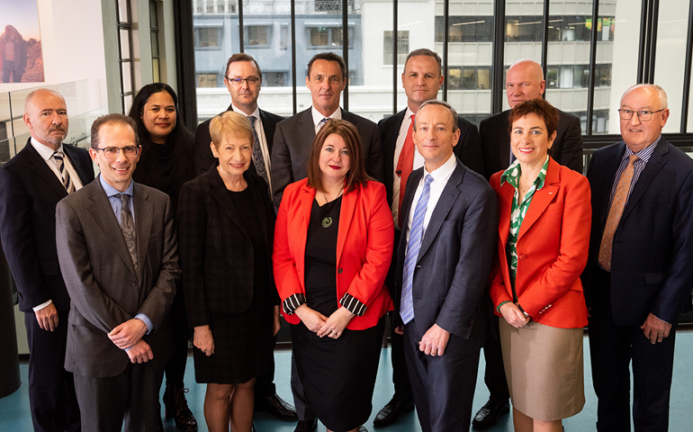 Portrait of the 12 people in MBIE's Senior Leadership Team, gathered inside with windows behind them.