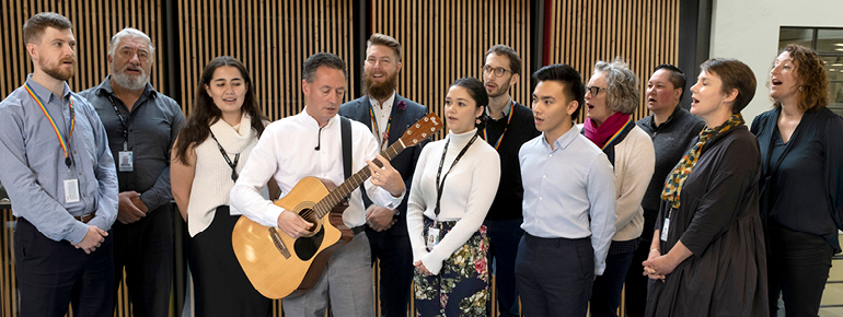 Decorative text: MBIE staff performing waiata