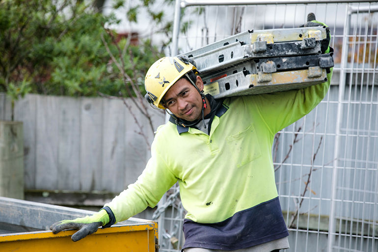 Construction worker carrying scaffold planks on his shoulder