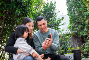 A family with two adults and a child looking at something on a phone together.