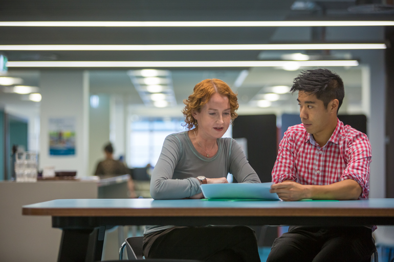 Two people in an office setting reviewing a document together.