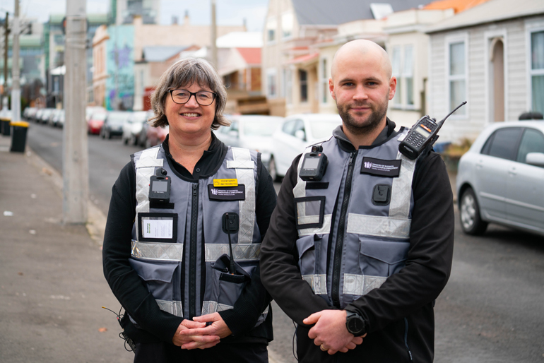 Two people in security vests in a neighbourhood.