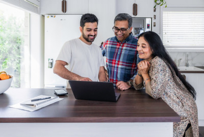 A family smiling and looking at a computer screen.