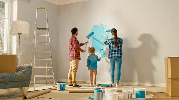 A man, woman and child painting a wall blue together.