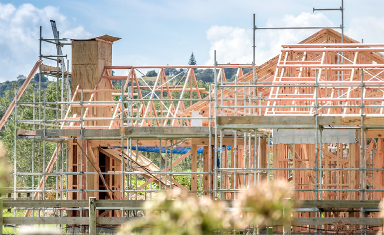 Photo of house under construction with timber framing and scaffolding.