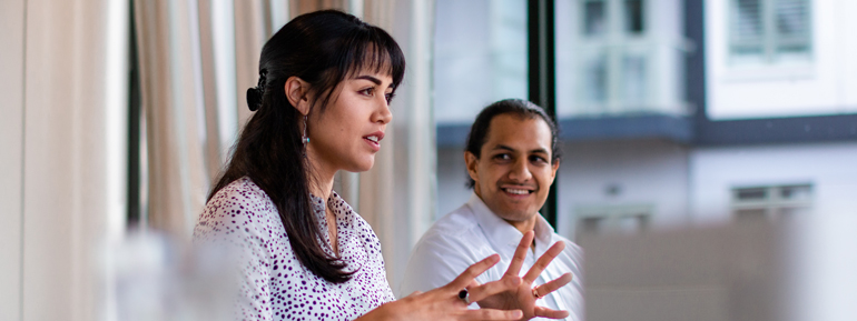 Woman gesticulating at work with man smiling in the background