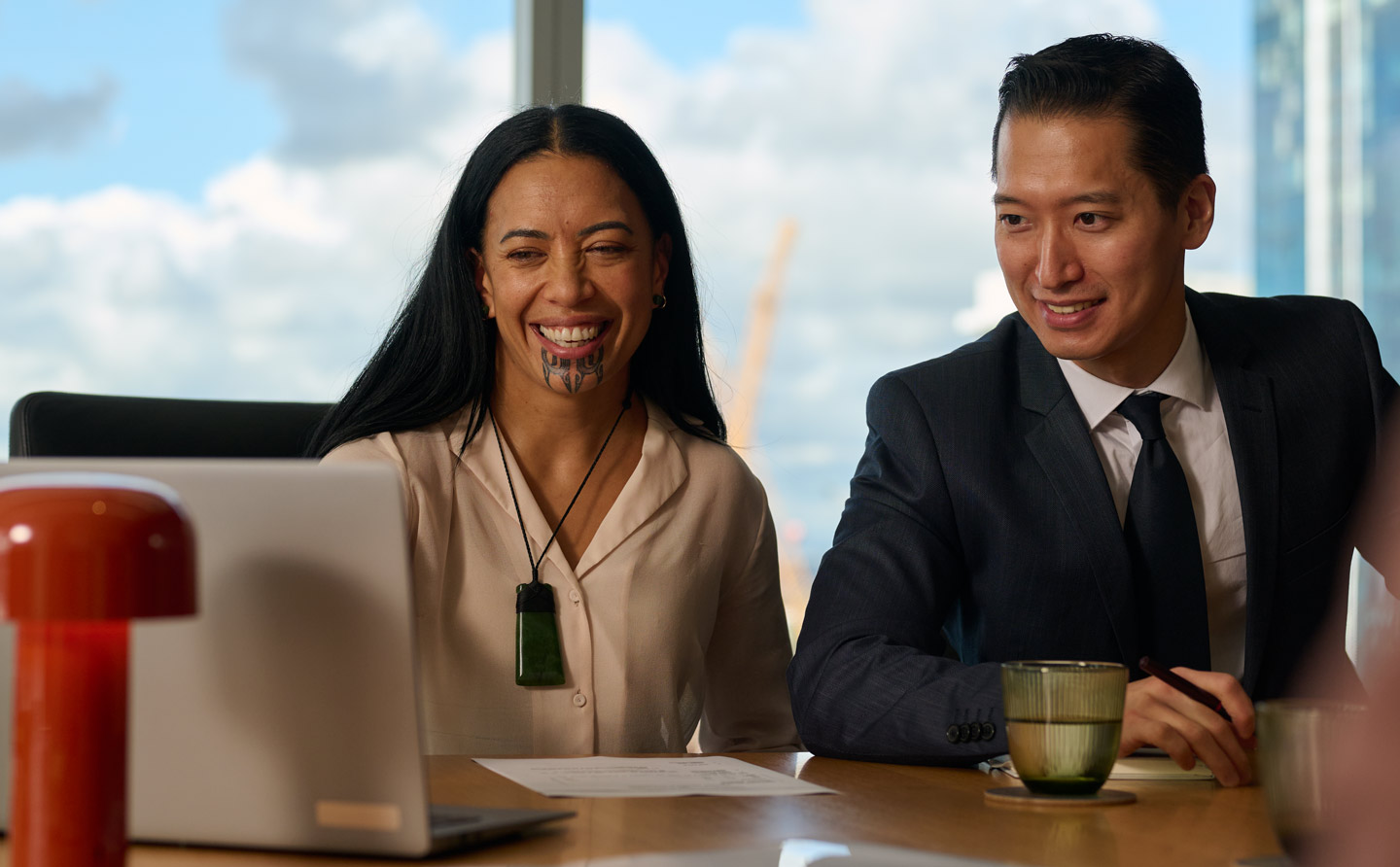 Wahine Māori with moko kauae and businessman looking at a laptop