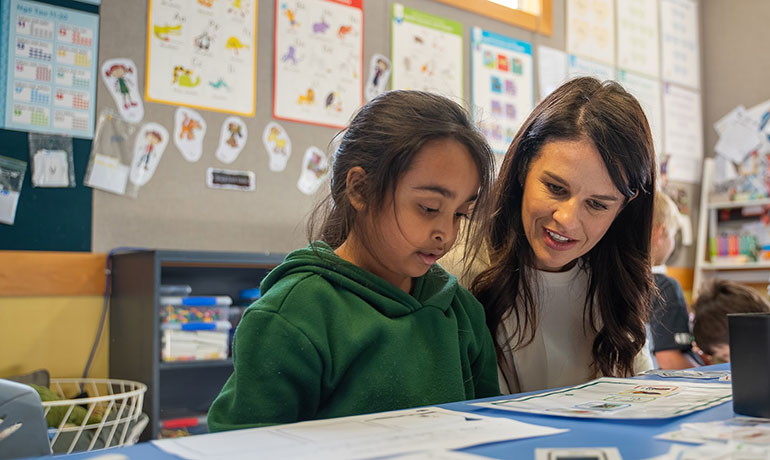 Hon Erica Stanford sitting with a student in the classroom