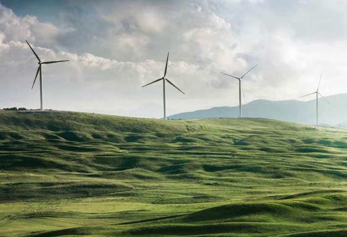 Wind turbines at the top of a rolling hill landscape..