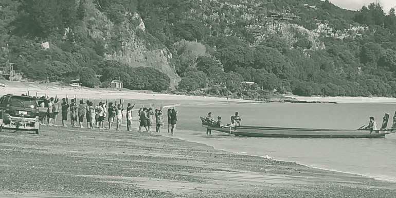 People launching a waka into the sea.