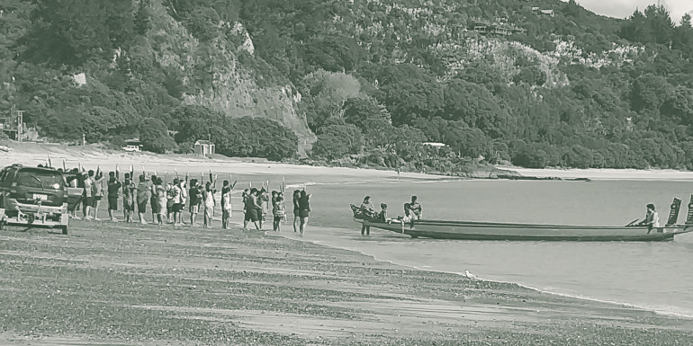 People launching a waka into the sea.
