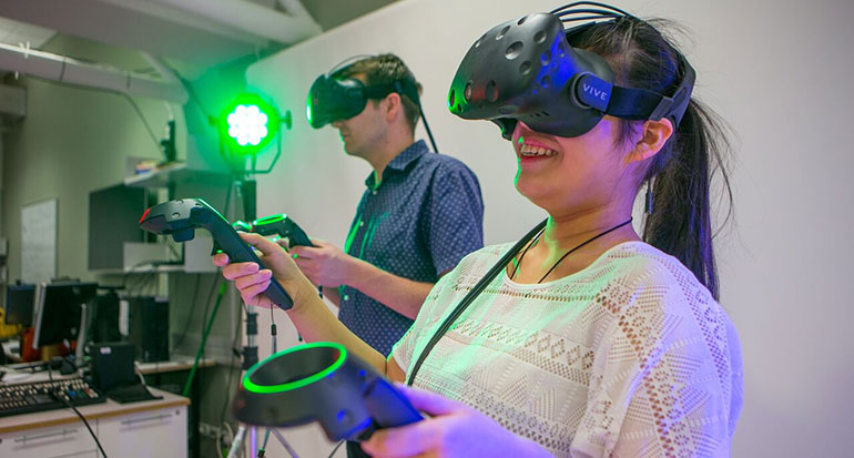 A young man and woman using virtual reality headsets and controllers