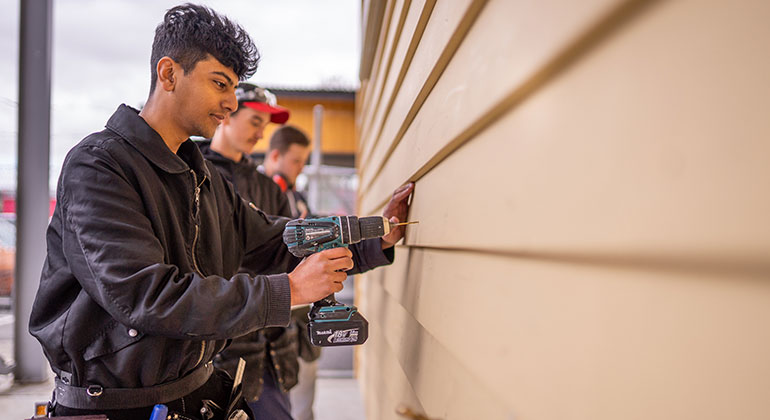 A young construction student practises using a drill.