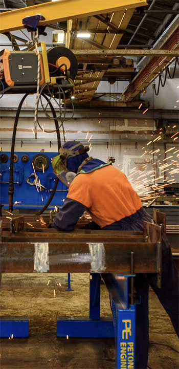 A worker in safety gear welding a steel beam