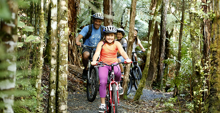 A family bikes through a forest