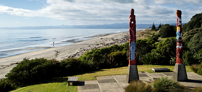 Two Māori Pou carvings overlooking a beach in the Eastern Bay of Plenty