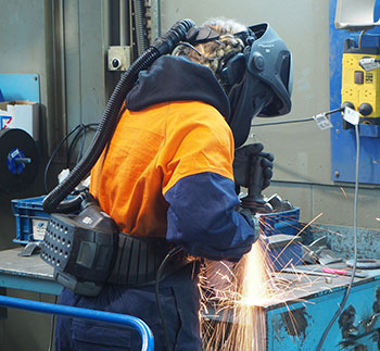 A factory worker uses a high-tech welding machine with sparks flying