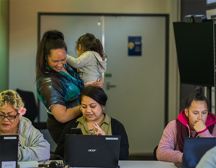 Two females and young child working on phone and laptop