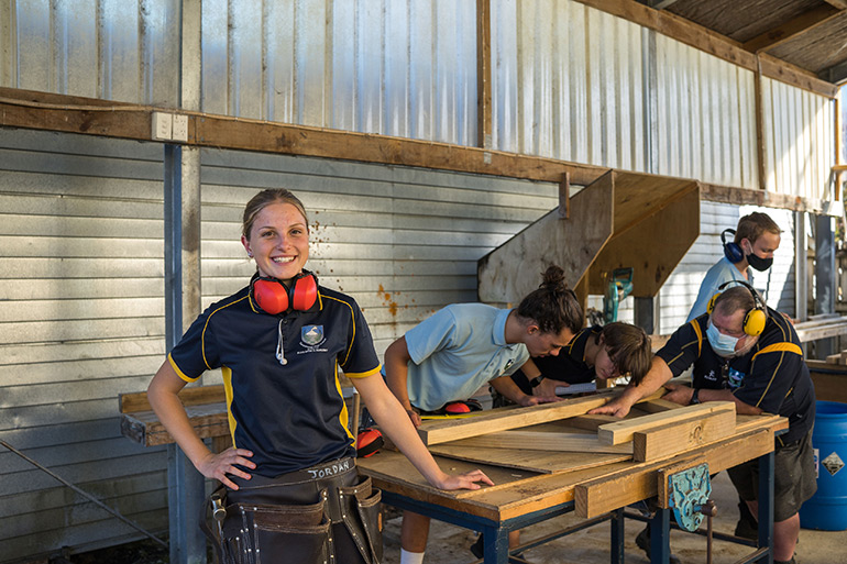 Young woman wearing earmuffs and tool belt.