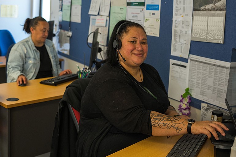 Woman working at a computer, smiling at the camera.