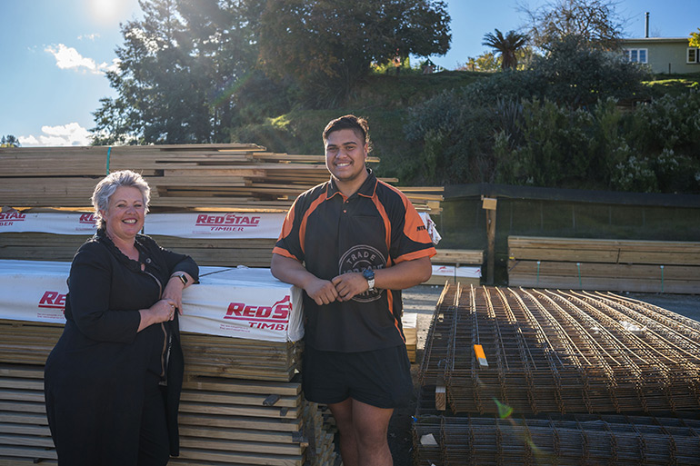 A woman and young man leaning on timber smiling.