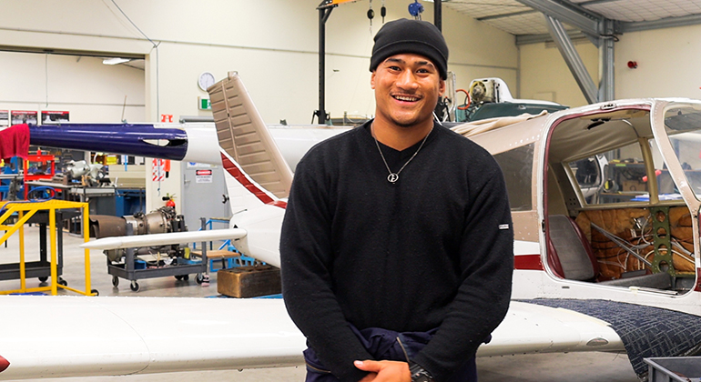 Young man standing in front of a light aircraft.