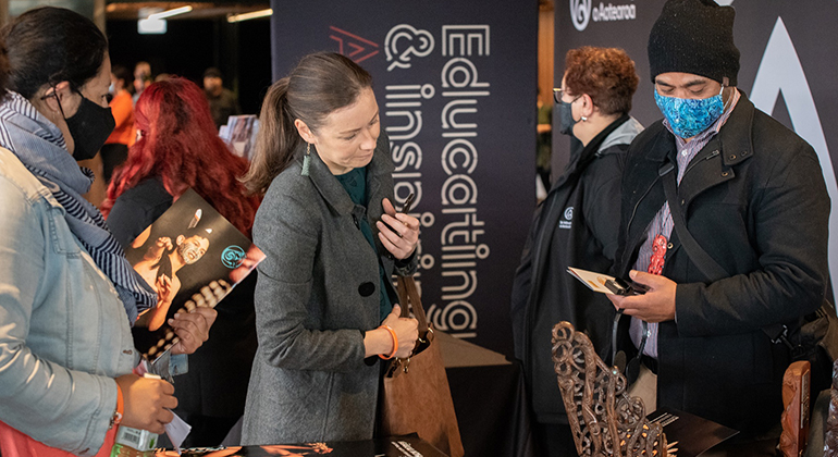 Two people inspecting an intricately carved Māori artwork.