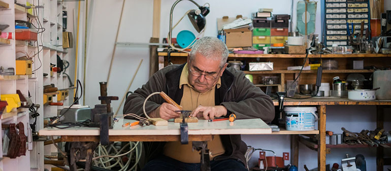 A photo of a man metal working at a bench.