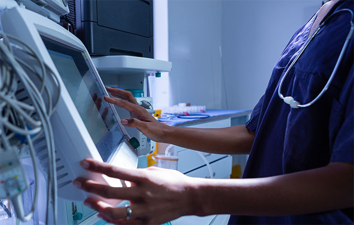 A health worker adjusting a bedside monitor
