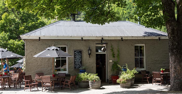 Tables with umbrellas outside a café in a historic stone building 