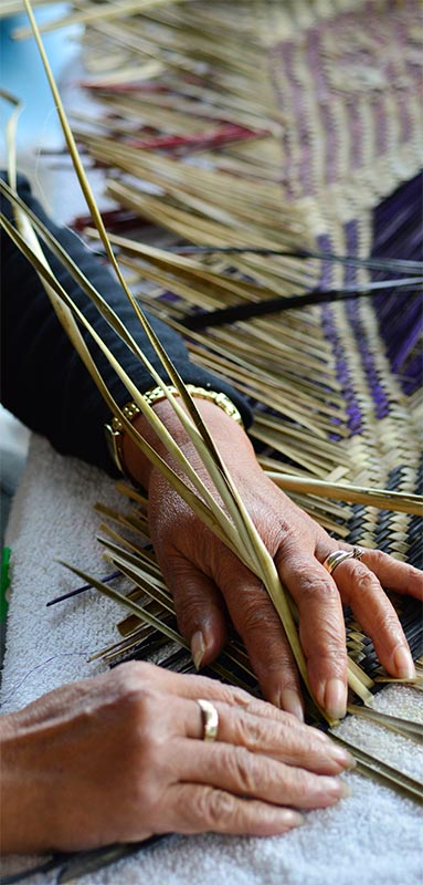 The hands of a woman weaving a flax artwork