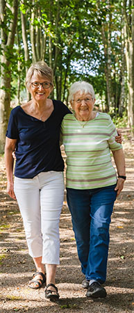 A woman walking on a path with her elderly mother