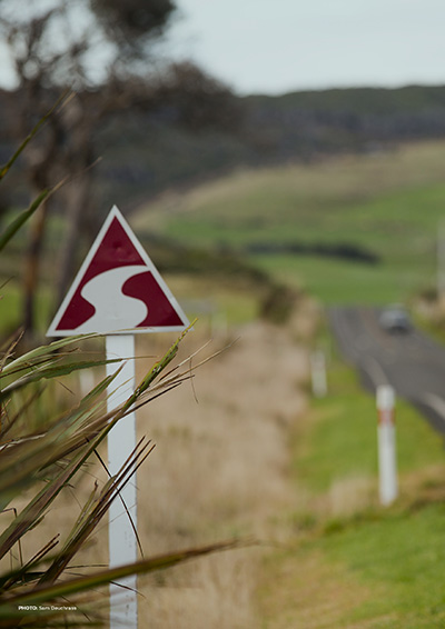 A sign marks a walking track with native bush in the distance