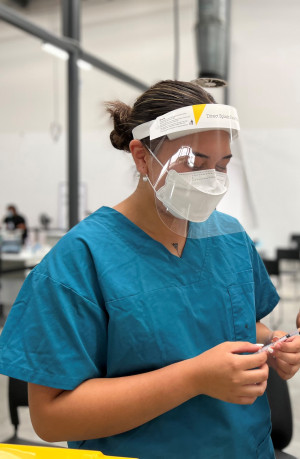 Vaccinator wearing PPE and holding needle