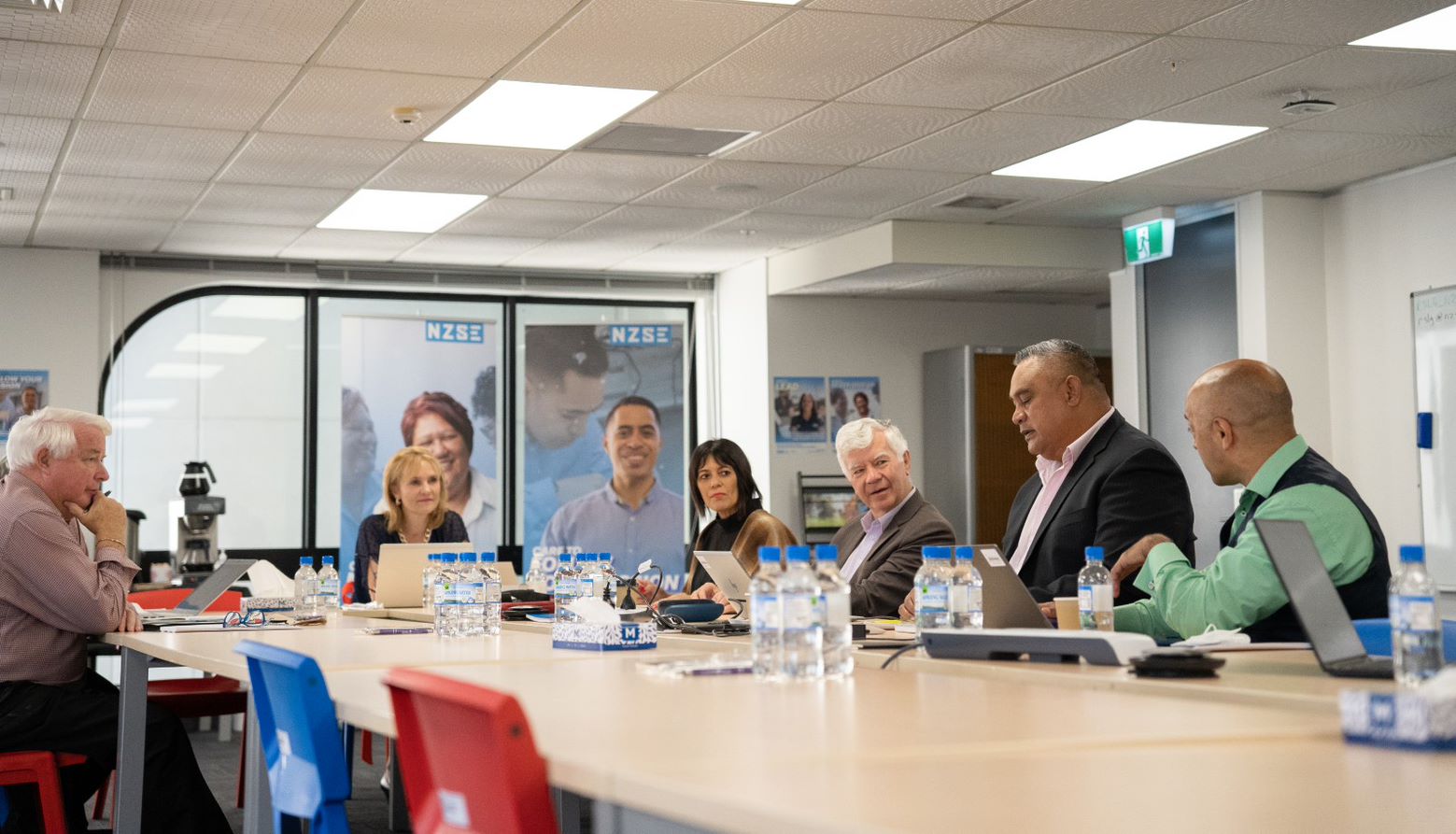 People sitting a table with laptops in front of them. Water bottles are also on the table.