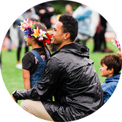 Father and daughter with flowers around her head at a fesival.