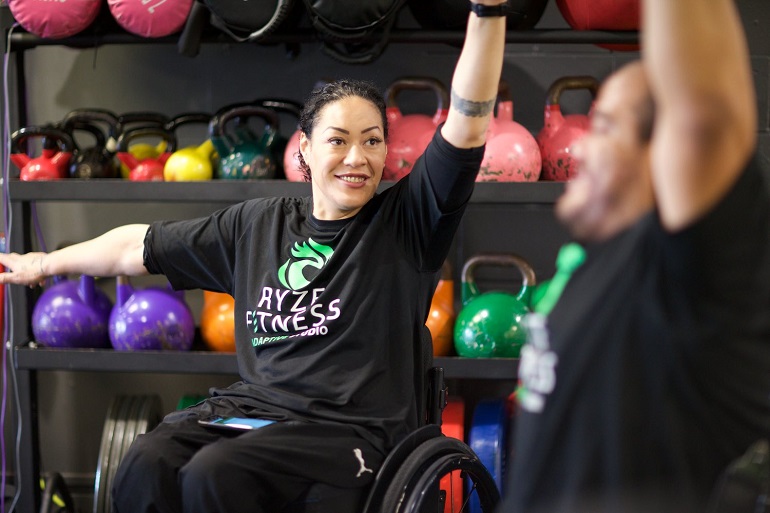 Female fitness intructor in wheel chair giving lessons.