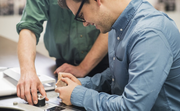 Two men looking at parts for a washing machine.