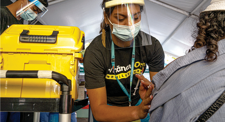 Young female vaccinator vaccinatiing a patient.