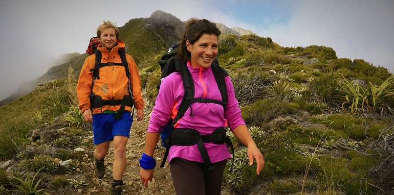 Photograph of male and female hikers walking in west coast bush.