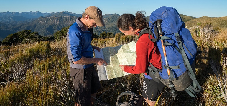 Photograph of two trampers studying a topographical map in Paparoa National Park.