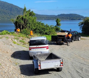 Photograph of two vehicles with trailers and wahine toa students doing weed control on the banks of the Buller River