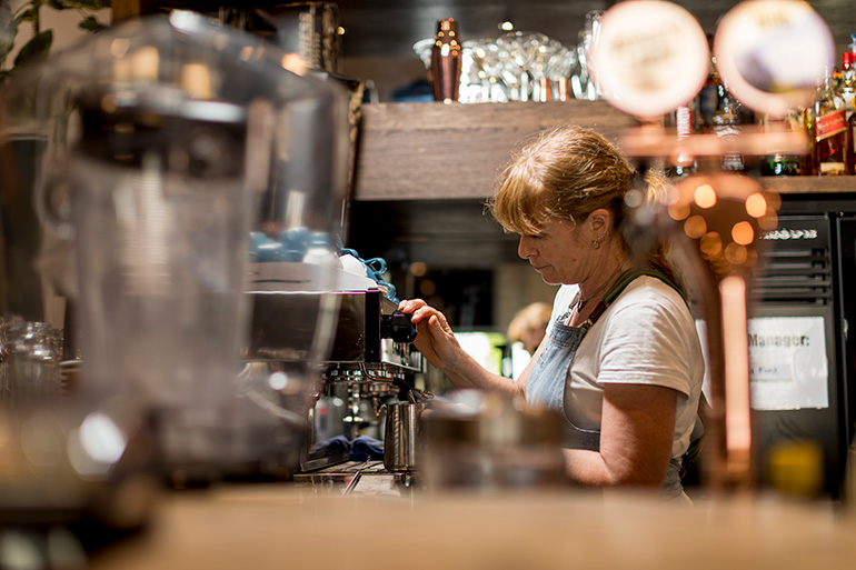 A woman making coffee in a cafe.