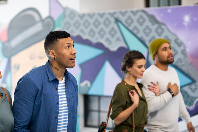 Three young adults showing a strong interest in someting happening in front of them