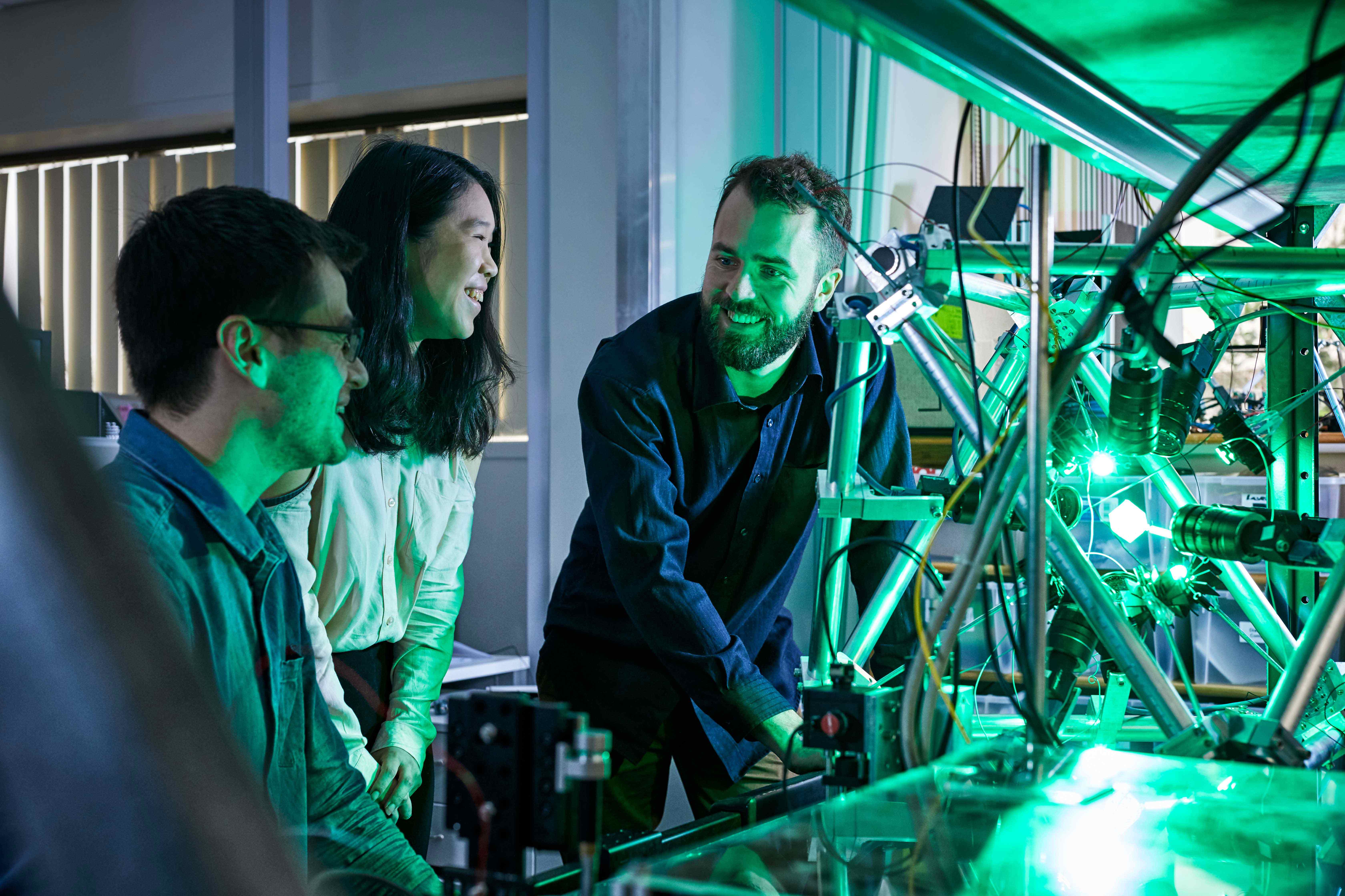 A group of three people talking and standing next to a machine