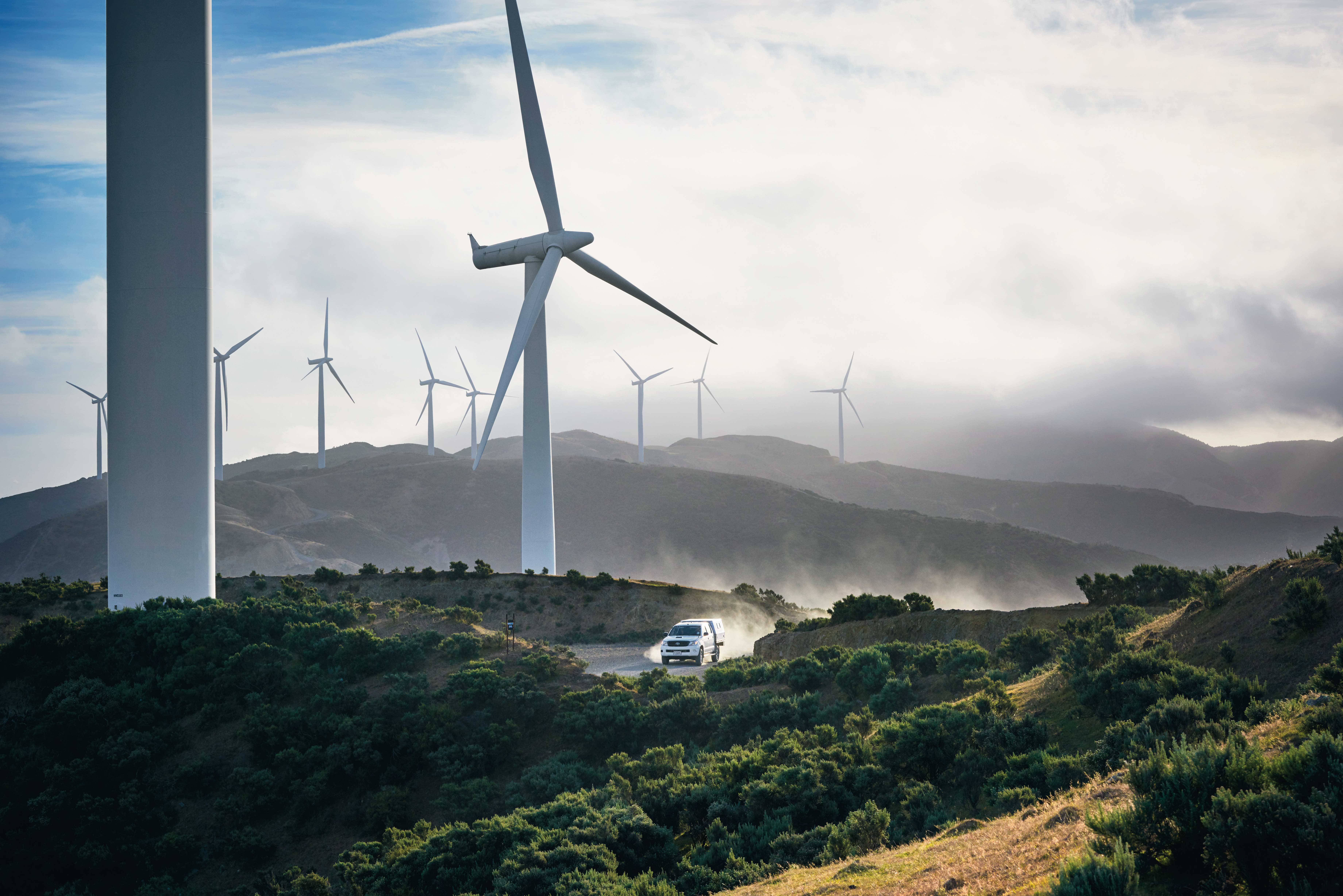 A wind turbine farm towering above a ute in the foreground